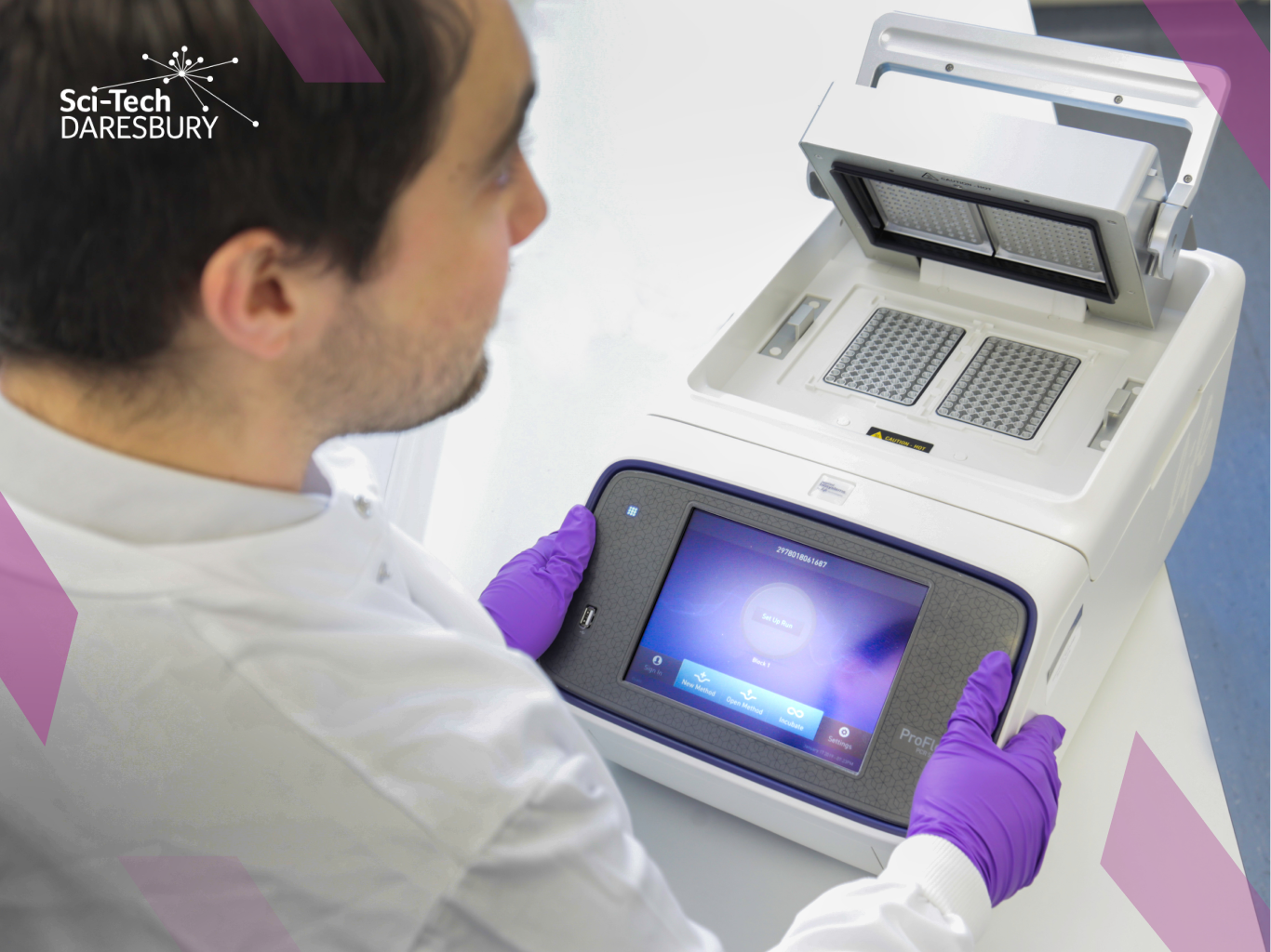 Lab Space Rental Costs – Featured Image Photo taken from over the shoulder of a man dressed in a white lab coat, working on some scientific machinery looking at data.